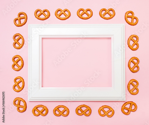Brezeles around wooden white frame on pink background. Top view, flat lay. copy space. photo