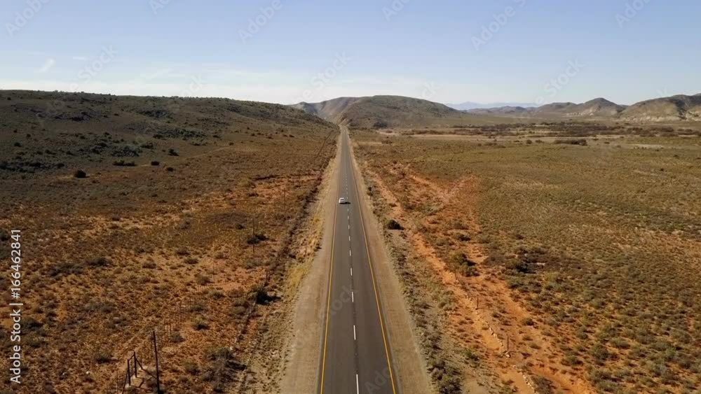 Aerial of car driving down long dirt road Aerial of car driving down long dirt road
