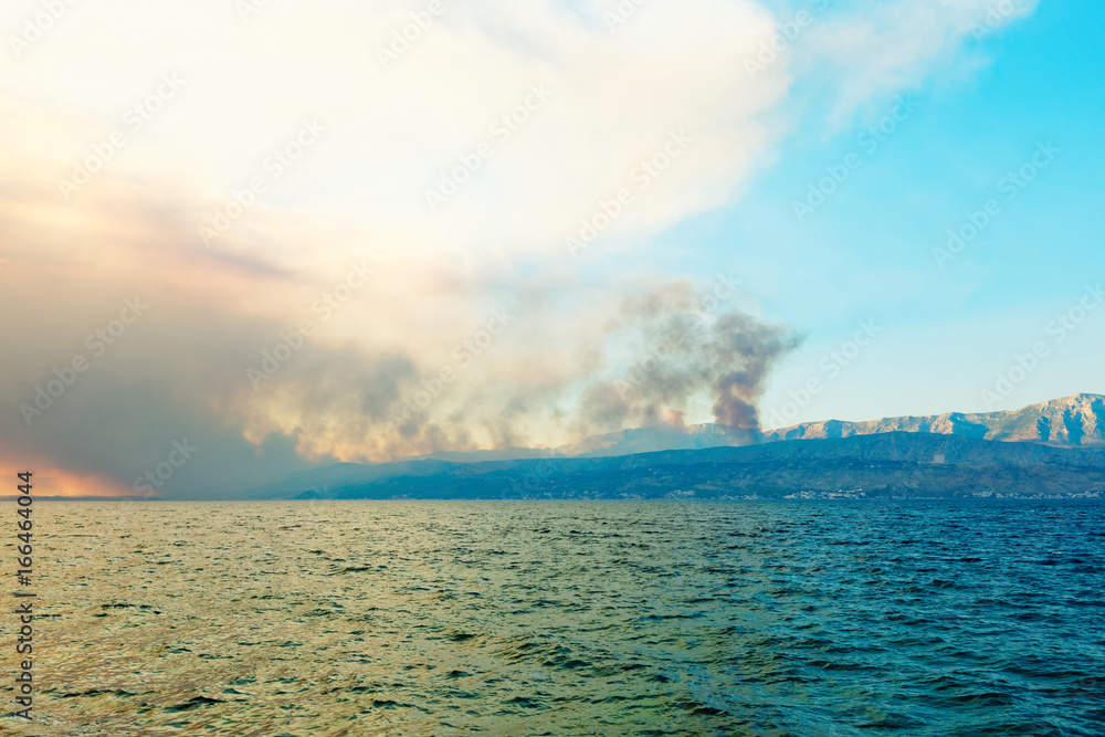 Coastline of Mediterranean sea with pillars of smoke above burning forests