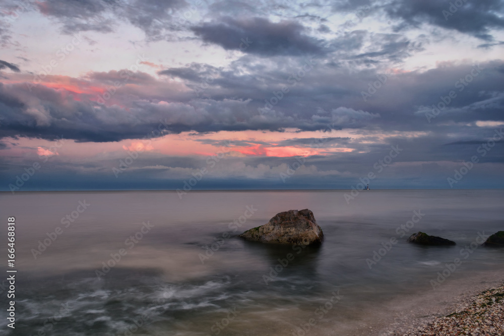 Obraz premium Seascape with stones, clouds and blured water