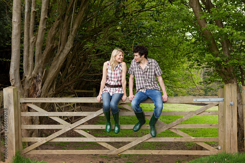 Young couple sitting on gate