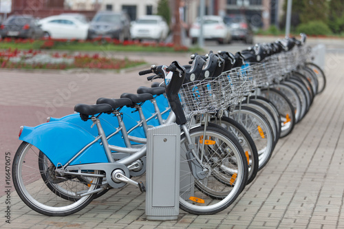 A rental bicycles stand in a row on a parking photo