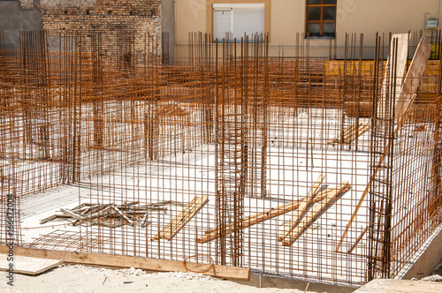 Building construction site foundation base with steel reinforcement prepared.