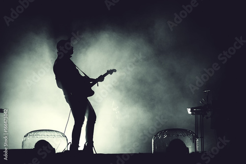 Silhouette of a guitar player in stage lights photo