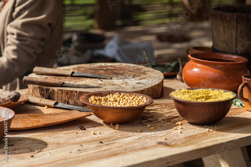 Chickpea and millet in the ceramic bowls on a wooden table among other kitchen utensils