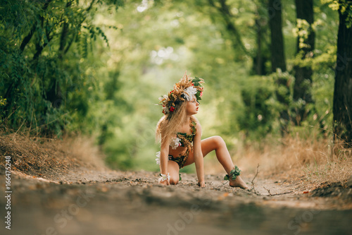 Fotografie Beautiful little girl in image of nymph dryad sits in forest road