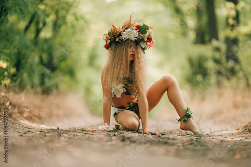 Bild auf Leinwand Beautiful little girl in image of nymph dryad sits in forest road