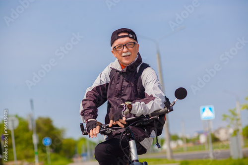 Senior man in a sports outfit sitting on a bench near bicycle. Portrait of man riding cycle