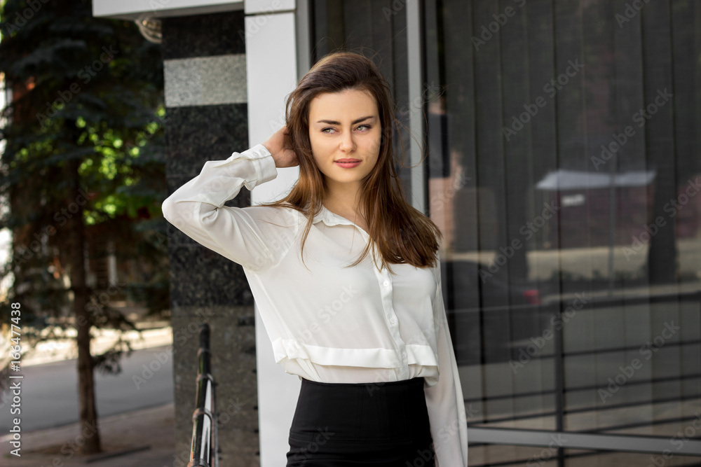 a charming young business woman standing on the street in a white shirt a charming young business woman standing on the street in a white shirt