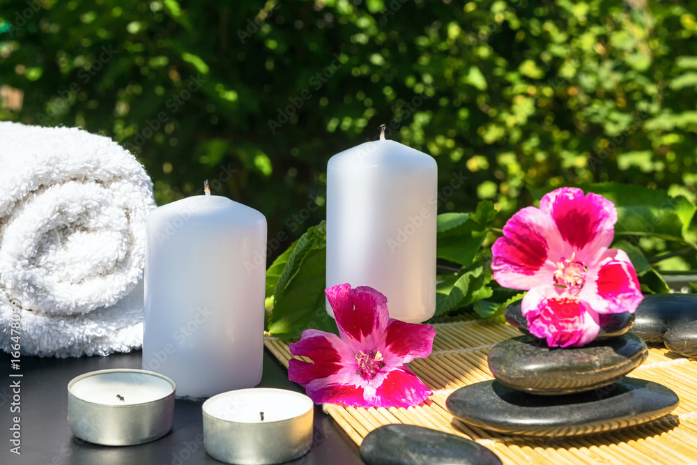 Candles, flowers, stones on a background of greenery for spa massage relaxation Candles, flowers, stones on a background of greenery for spa massage relaxation