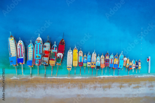 Fototapeta Naklejka Na Ścianę i Meble -  Boats. Aerial view of colorful boats in mediterranean sea in Oludeniz, Turkey. Beautiful summer seascape with ships, clear azure water and sandy beach at sunrise. Top view of yachts from flying drone