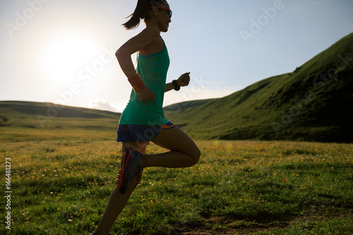 Fototapeta Naklejka Na Ścianę i Meble -  young fitness woman runner running on sunset grassland trail