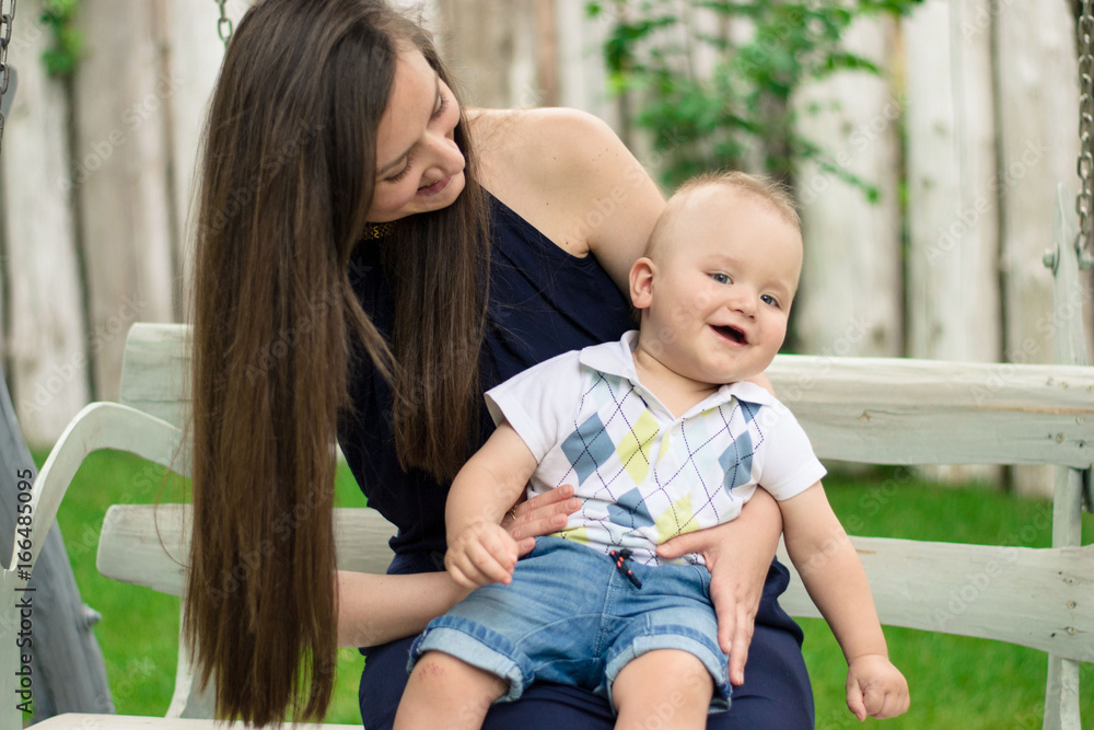 Happy woman playing with baby that siting on her knees Happy woman playing with baby that siting on her knees
