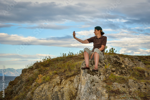 Female middle aged hiker taking selfie on the top of a mountain 