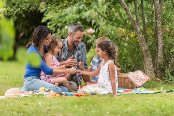 Cheerful family sitting on the grass during un picnic in a park