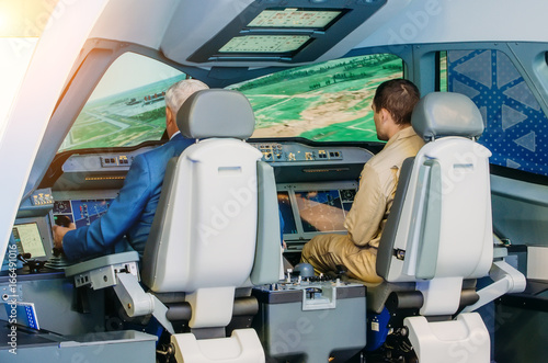The simulator of a passenger aircraft with a cockpit and pilots photo