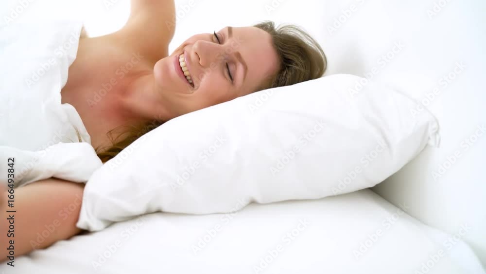 Cute girl sleeping in bed waking up stretching and smiling Cute girl sleeping in bed waking up stretching and smiling