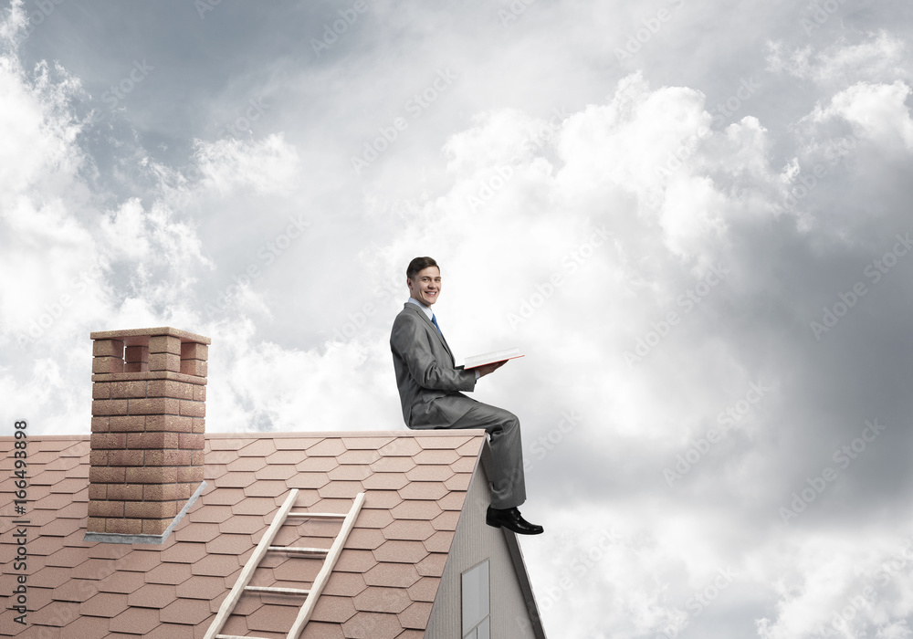 Student guy in suit on brick house roof reading book Student guy in suit on brick house roof reading book