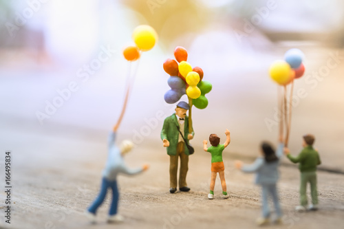 Family and kid concept. Group of children miniature people figure standing and walking around a man balloon seller