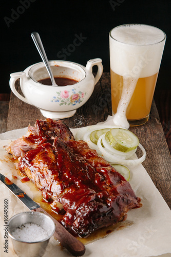 Smoked bbq baby back ribs paired with beer on dark background photo