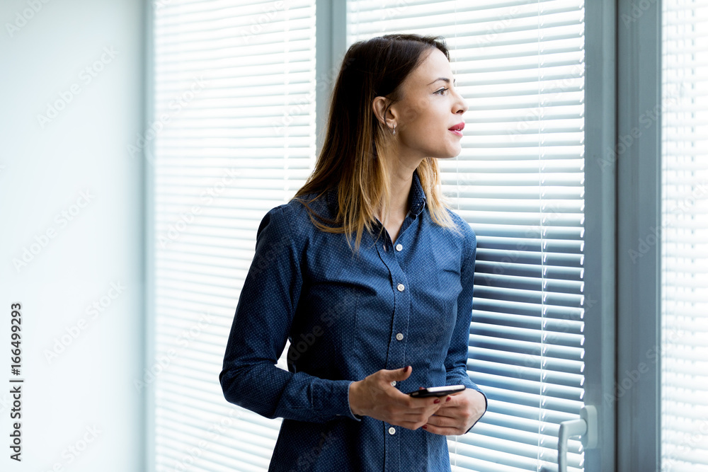 Young woman peering the Venetian blinds