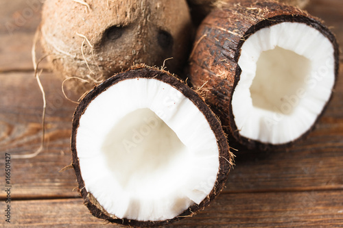 Close up half broken coconut with fresh white pulp. Exotic fruits of different countries on wooden background