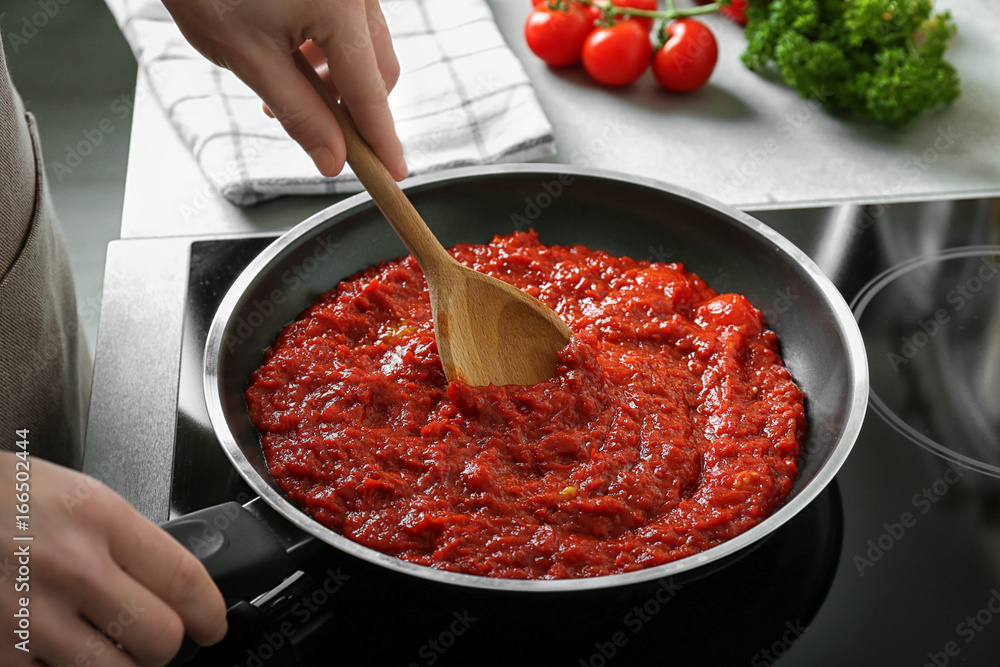 Woman preparing tomato sauce in frying pan Woman preparing tomato sauce in frying pan