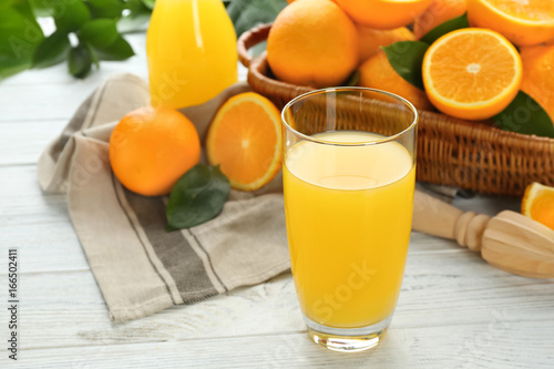 Glass of fresh orange juice with fruit on wooden background