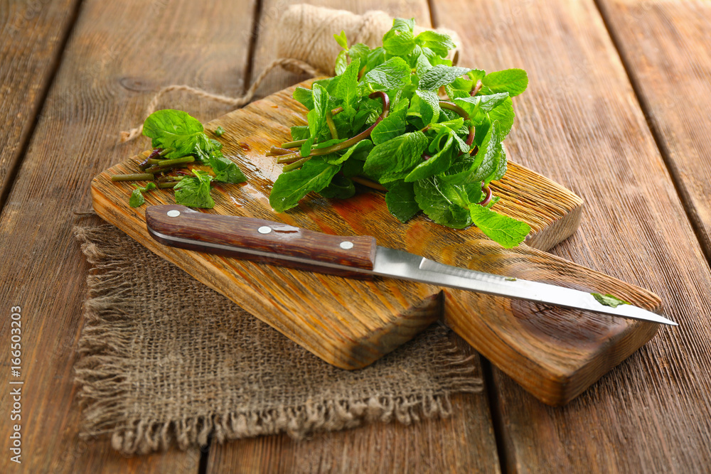 Lemon balm with knife on wooden board