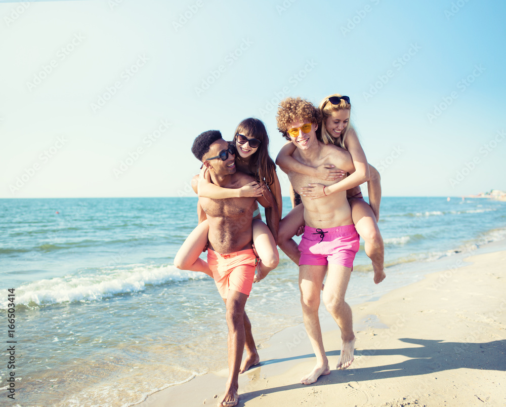 Happy smiling couples playing at the beach