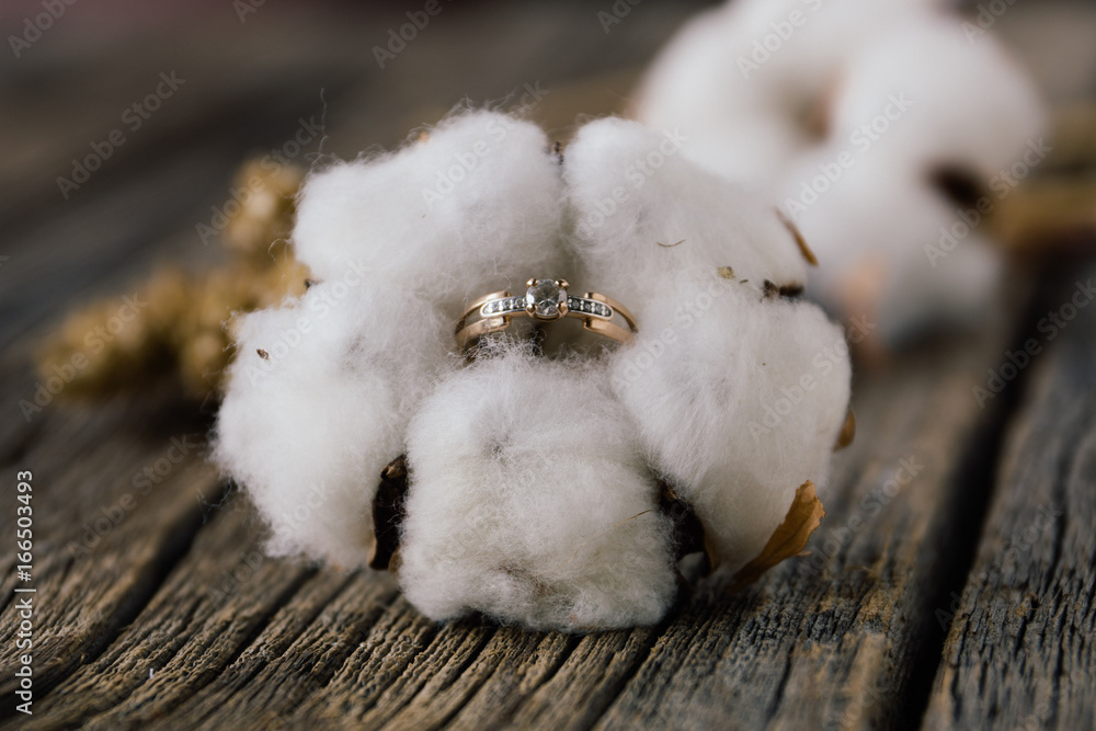 Engagement ring in cotton flower on wooden background. Natural. Concept of autumn rustic wedding Engagement ring in cotton flower on wooden background. Natural. Concept of autumn rustic wedding