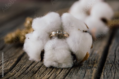 Engagement ring in cotton flower on wooden background. Natural. Concept of autumn rustic wedding