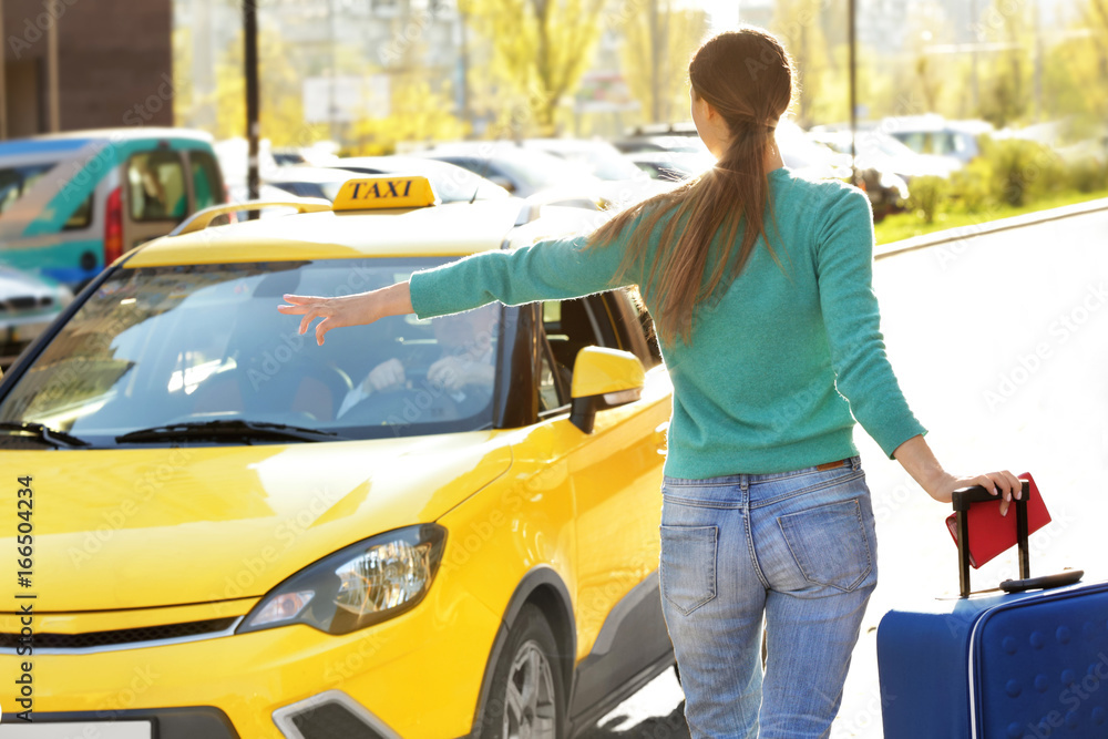 Young woman with luggage catching taxi on street Young woman with luggage catching taxi on street