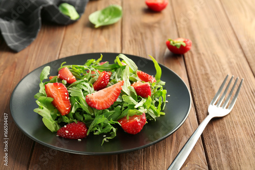 Tasty salad with arugula and strawberry on plate