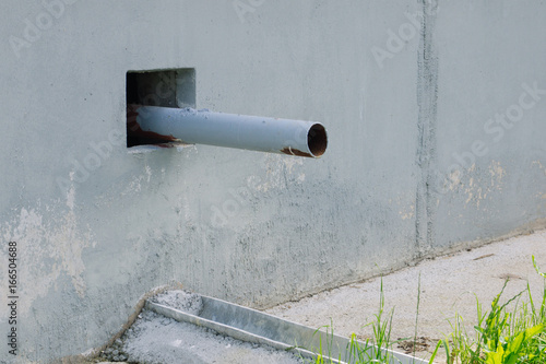 Drainpipe. Gray wall with drain pipe and gutter. Draining the water from the roof. Natural. Water drain or ditch on the road