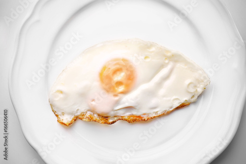 Plate with over hard fried egg on light background