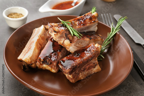 Plate with delicious pork ribs and rosemary on table, closeup