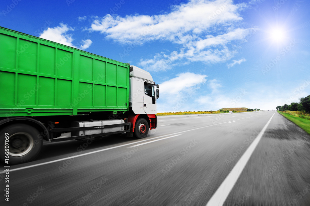 Truck driving fast with the container on the road against sky