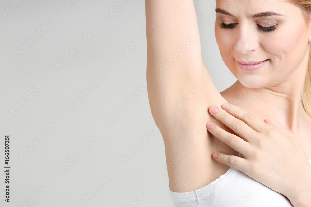 Beautiful young woman on light background. Concept of using deodorant Beautiful young woman on light background. Concept of using deodorant