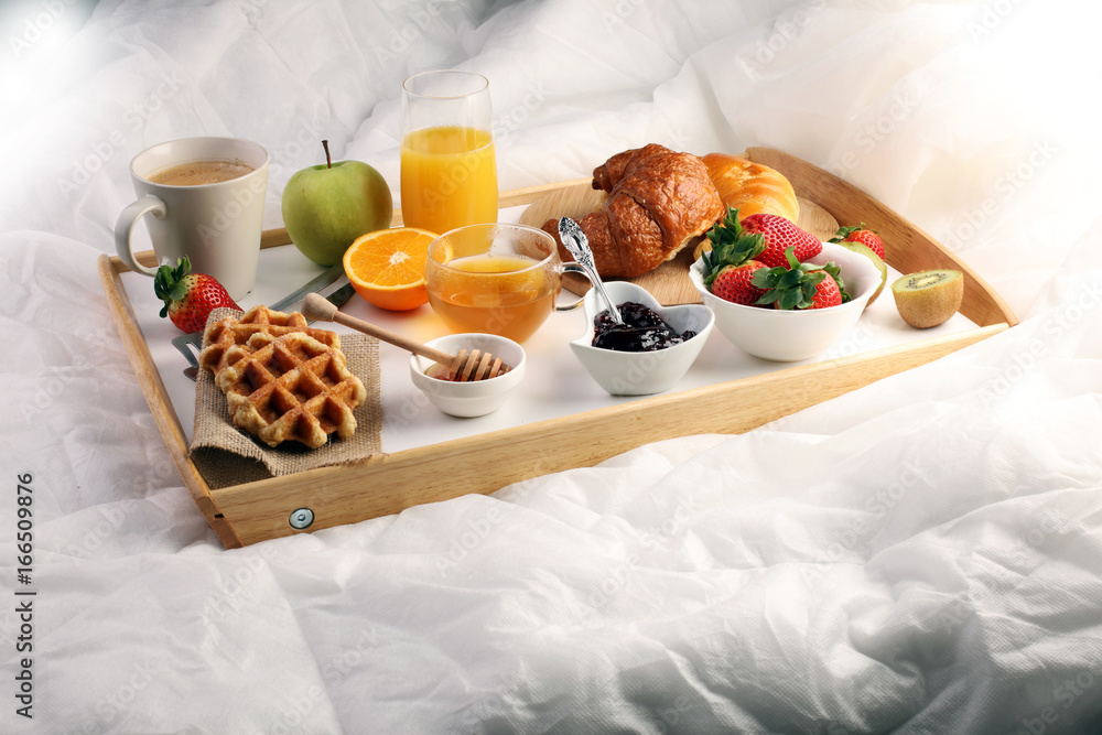breakfast in bed with fruits and pastries on a tray -waffles, croissants, coffe and juice breakfast in bed with fruits and pastries on a tray -waffles, croissants, coffe and juice