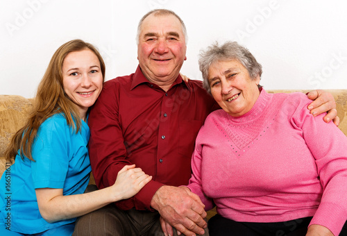 Smiling elderly couple and young caregiver