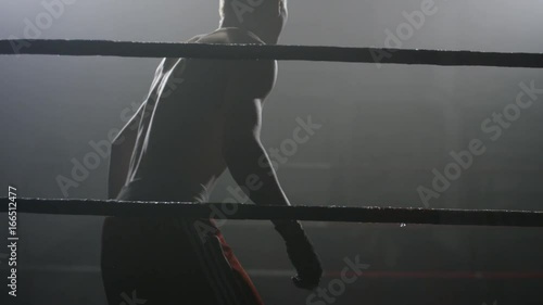 Boxer walks into the ring on training. Preparation for training. Fighter at the ring on the black backgrount photo