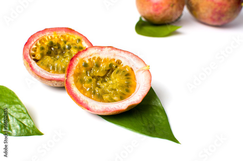 Halved passion fruit with leaves on white