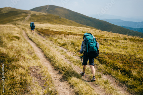 Happy healthy traveler with backpacks reaching top in carpathian mountains. Hiking activity. Tourist adventure. Alpine walking. Vacation trip. Lifestyle. Week end journey. Discover Ukraine. Hard walk photo