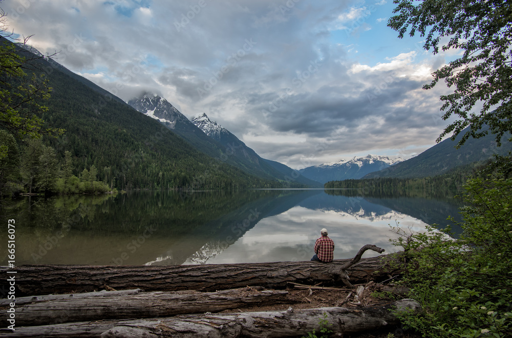 Man Sitting on Edge of Peaceful Lake