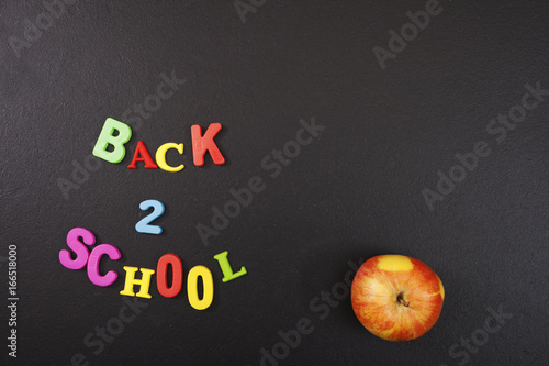 Back 2 school colorful letters and an apple on blackboard background with copyspace for your text. Concept for your design, banner, web, flyer