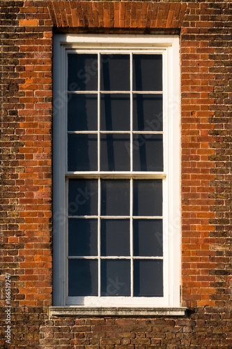 Close-up of white window in red Tudor building brick wall