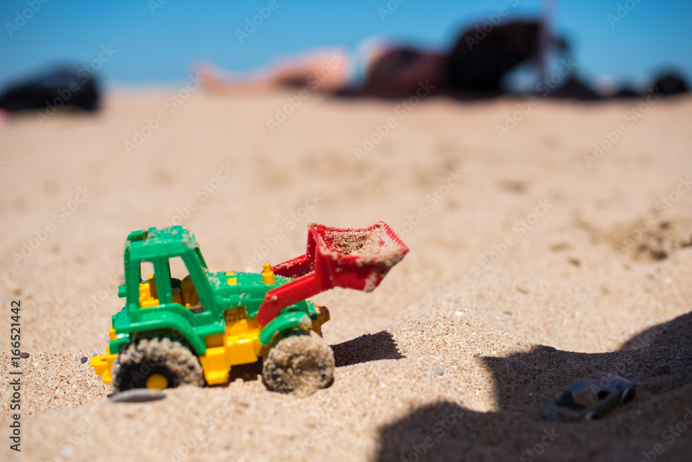 Tractor toy on the sandy beach Tractor toy on the sandy beach