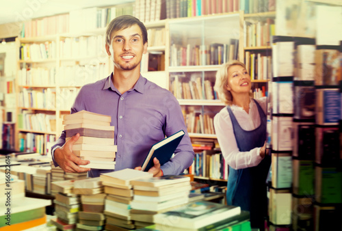 Young smiling man having book pile in hands
