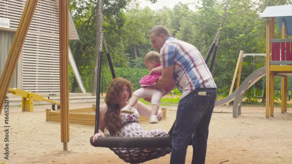Man swinging his daughter and his wife on a swing Man swinging his daughter and his wife on a swing
